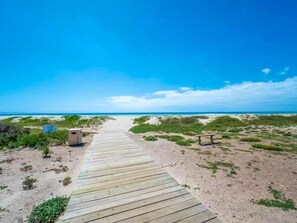A wooden boardwalk leading to a beach with a small structure and a bench. - Kabeljauws Beachfront Luxury Apartments (Jeffreys Bay)