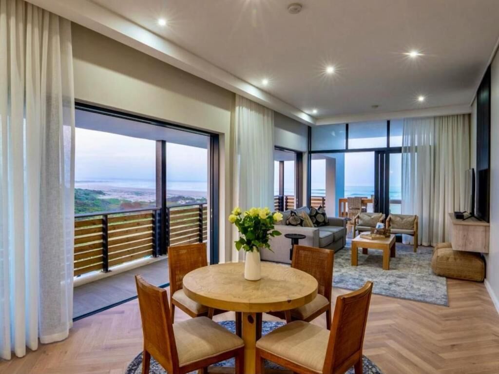 Un salon moderne avec un coin repas, de grandes fenêtres et une vue sur la mer.