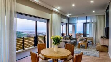 Un salon moderne avec un coin repas, de grandes fenêtres et une vue sur la mer.