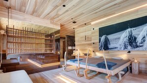 A modern interior with a wooden ceiling, a large painting, and a bed with a wooden frame. - Oberwidner Aura – Luxury Suite in Sarntal (Sarntal)