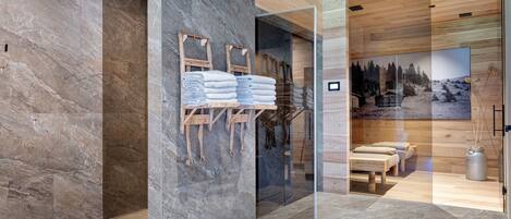 Une salle de bain moderne avec un mur en pierre, des poutres en bois et une cloison en verre.