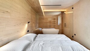 Ein modernes Schlafzimmer mit einer Holzwand, einem Bett mit weißer Bettwäsche und einer eingebauten Sitzbank.
