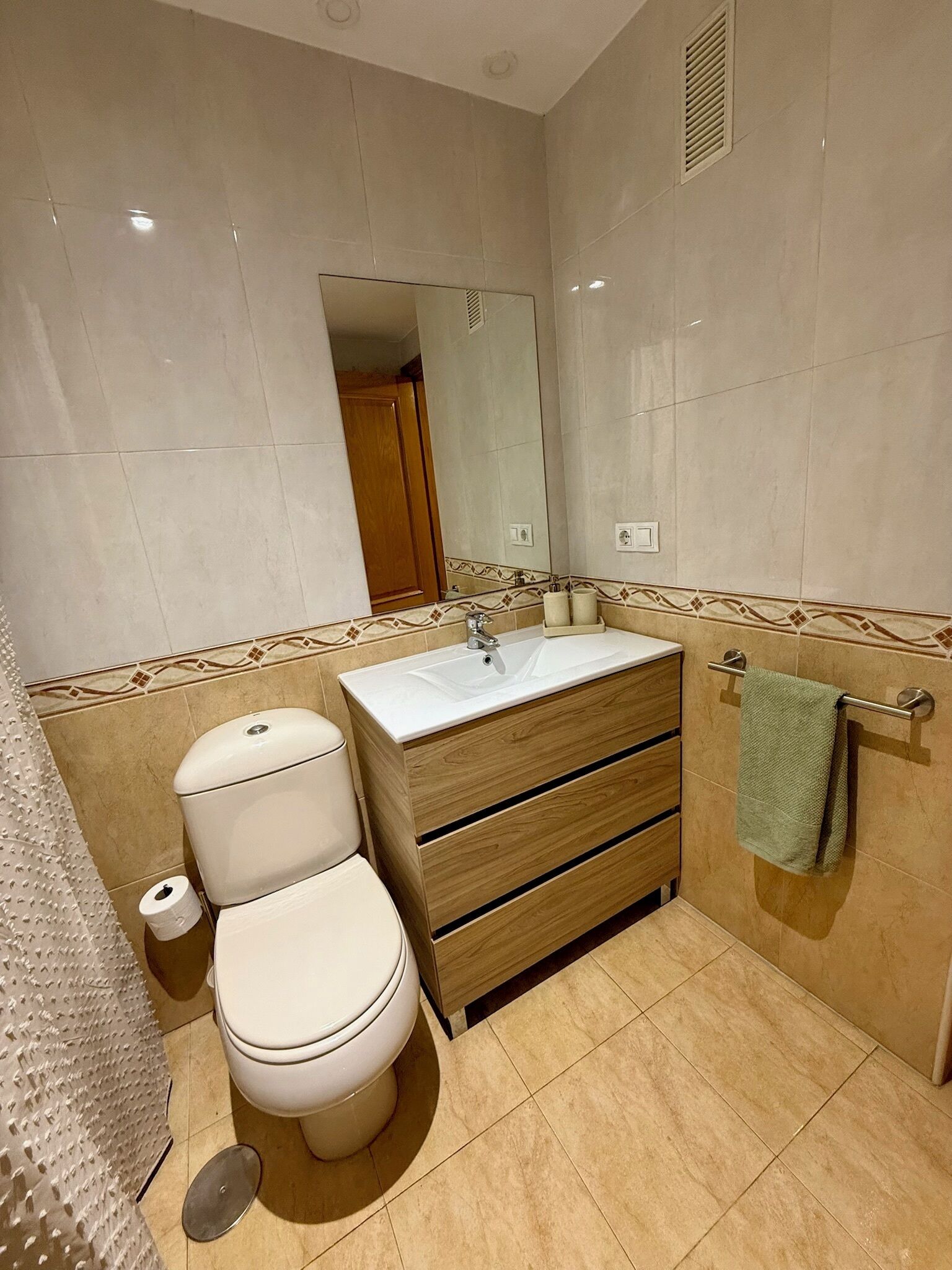 A bathroom with a toilet, sink, and shower area.