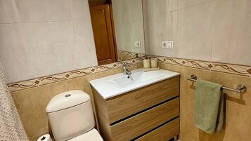 A bathroom with a toilet, sink, and shower area.