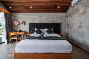 A bedroom with a wooden headboard, a bed with white bedding, a desk with a chair, and a large window with curtains. - Unique and Stylish Villa w/ Plunge Pool Near beach (Canggu)
