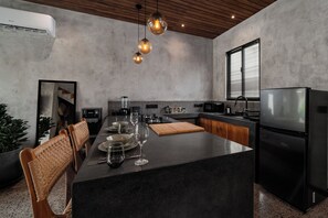 A modern kitchen with a central island, black appliances, and a herringbone-patterned backsplash. - Unique and Stylish Villa w/ Plunge Pool Near beach (Canggu)