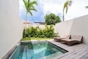 A swimming pool with a wooden deck, surrounded by lush greenery and a clear sky. - Unique and Stylish Villa w/ Plunge Pool Near beach (Canggu)