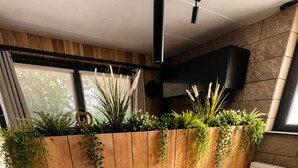 Un comedor con una mesa de madera, dos sillas y una planta en maceta en la pared.
