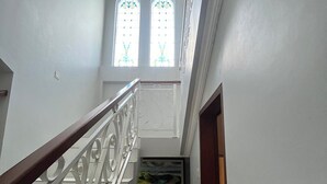 Eine Treppe mit Metallgeländer führt zu einer Zwischenebene mit einer Tür und einem Fenster mit Dekorglas.