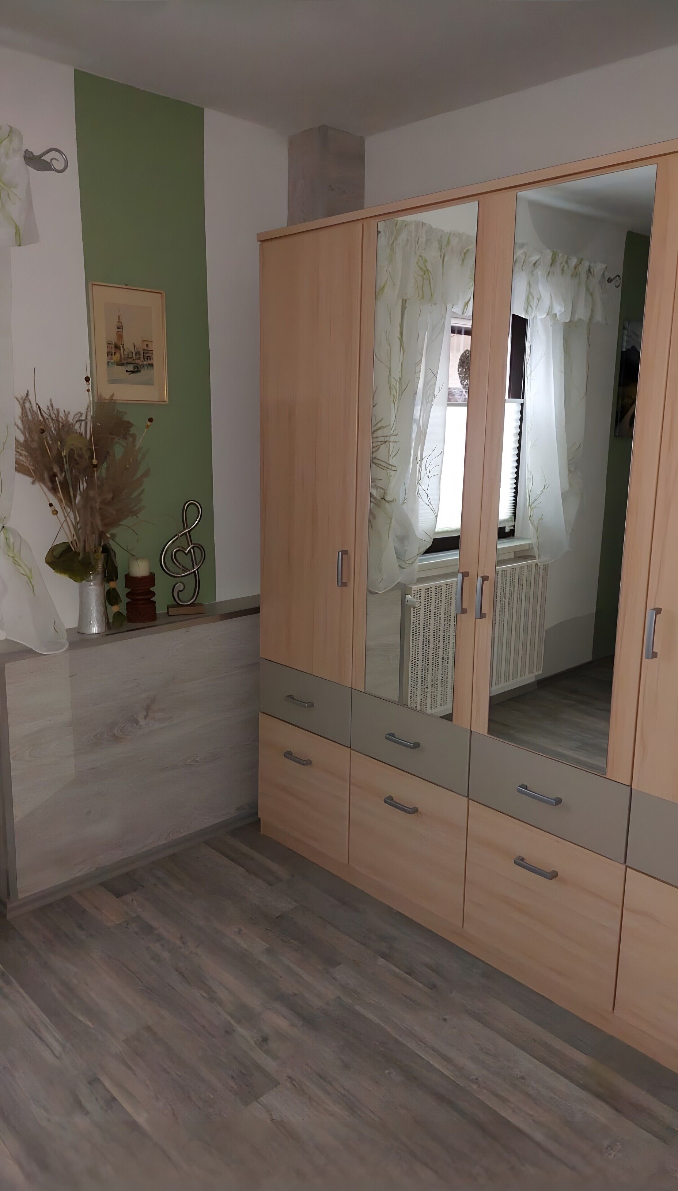 Une pièce avec une armoire en bois, un radiateur et un tableau encadré accroché au mur.