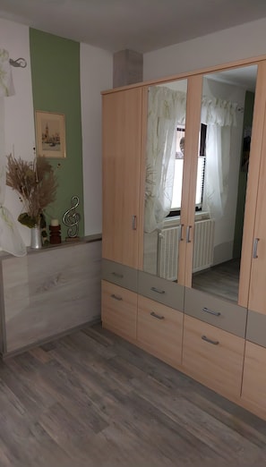 Une pièce avec une armoire en bois, un radiateur et un tableau encadré accroché au mur.
