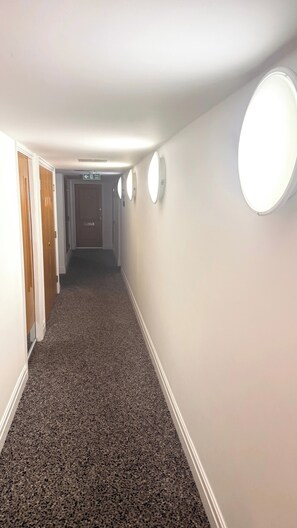 A hallway with carpeted flooring, white walls, and doors on the left. - Luxury Central London Apartment Paddington (London)