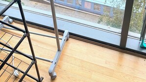 Näkymä ikkunasta, josta avautuu näkymä rautatieasemalle, ja etualalla on metallinen rakennelma.
