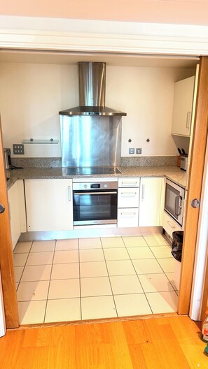 A compact kitchen with a stainless steel range hood, a built-in oven, and a microwave. - Luxury Central London Apartment Paddington (London)
