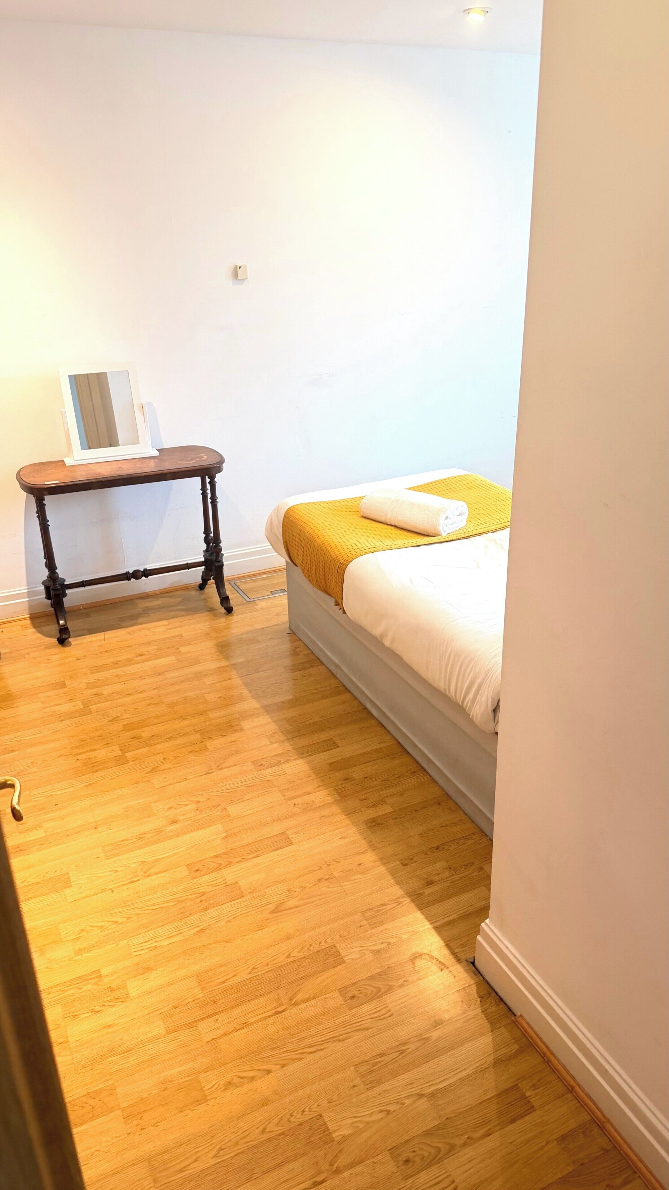 Un dormitorio con cama, mesita de noche y espejo.