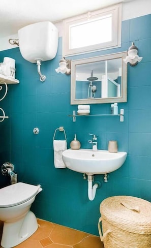 A bathroom with a toilet, sink, mirror, and a towel rack.