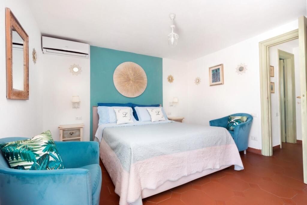 Une chambre à coucher avec un lit, deux chaises, une horloge murale et une porte.