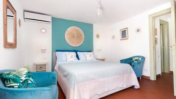 Une chambre à coucher avec un lit, deux chaises, une horloge murale et une porte.