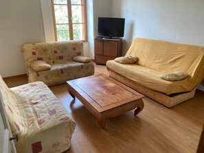 A living room with two sofas, a coffee table, and a television on a wooden cabinet.