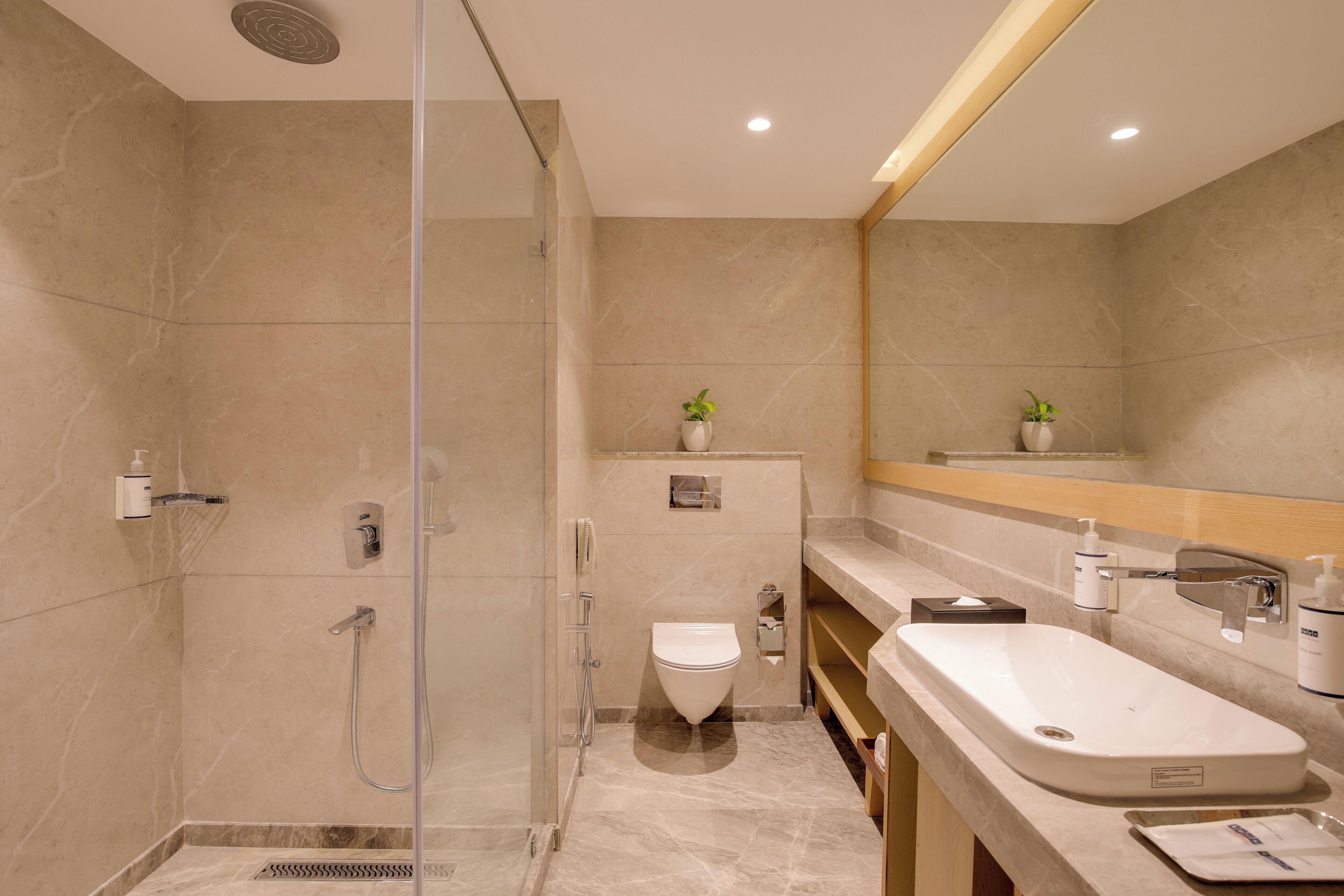 Un baño moderno con ducha de vidrio, inodoro, lavamanos y espejo.