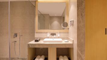 A modern bathroom with a large mirror, a sink, and a shower.