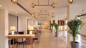 Un vestíbulo de hotel con comedor, múltiples candelabros y plantas en macetas.