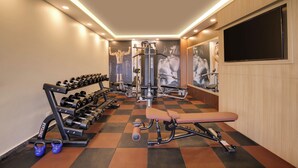 Un gimnasio con máquinas de pesas, mancuernas y un banco.