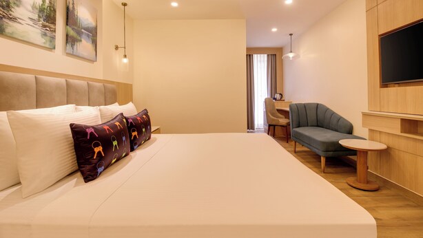 Habitación de hotel con una cama grande, un escritorio, una silla y un televisor de pantalla plana montado en la pared.