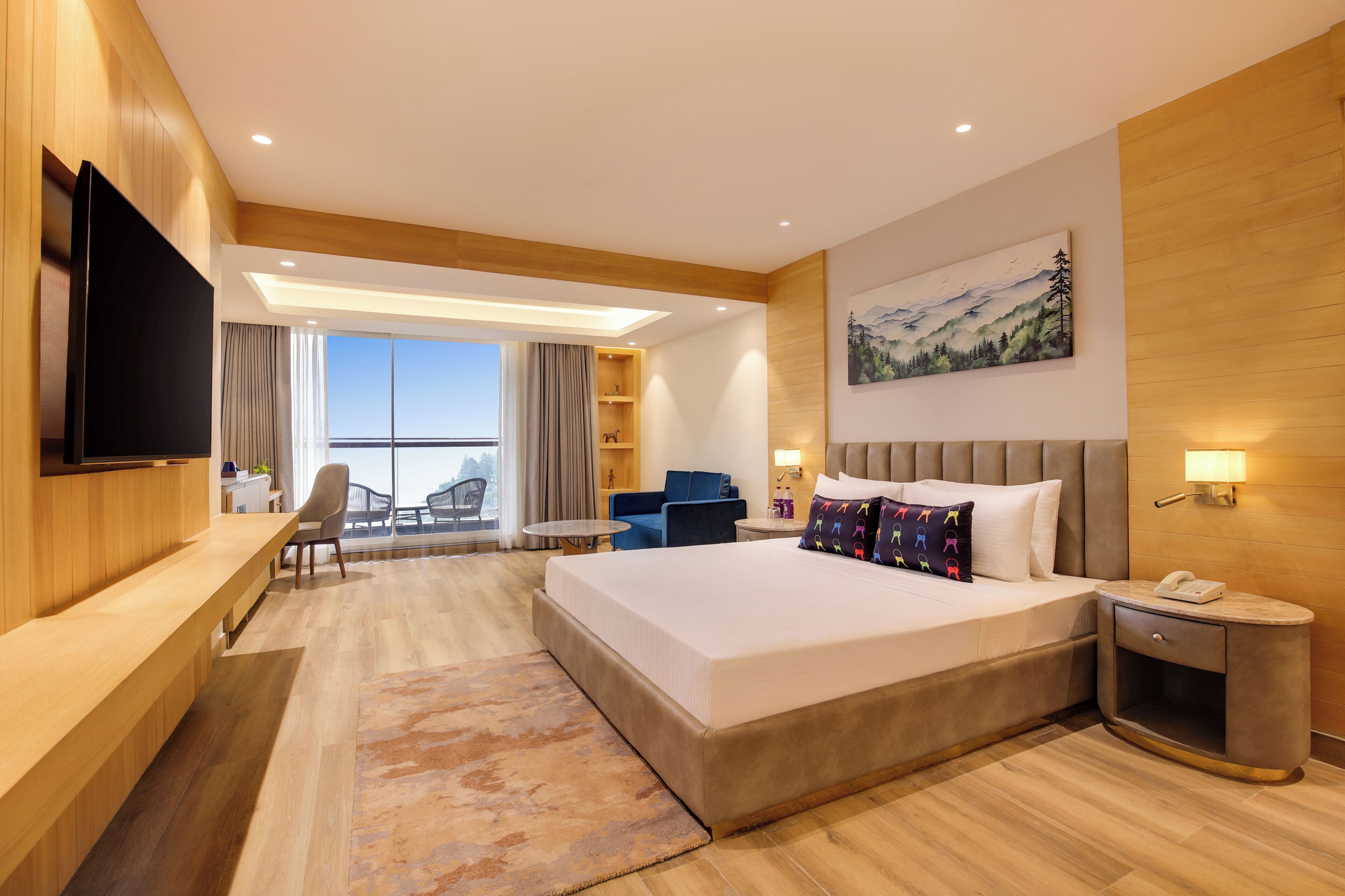 A hotel room with a large bed, a desk, a TV, a chair, a sofa, a painting, and a view of the outdoors.