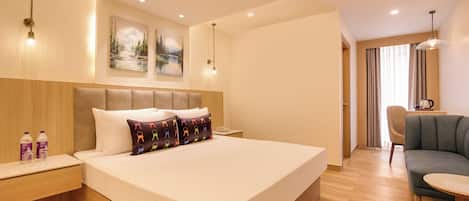 Habitación de hotel con una cama grande, mesitas de noche, un escritorio, una silla y un área de comedor.