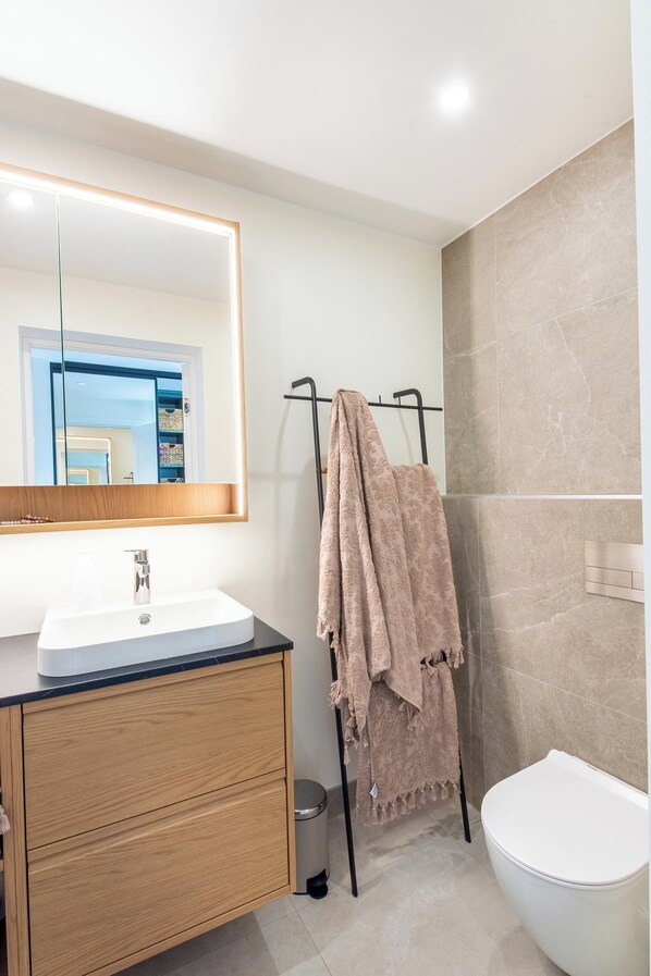 A modern bathroom with a white sink, wooden cabinet, and a towel rack.