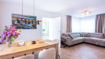 Una sala de estar moderna con comedor, un sofá y un cuadro en la pared.