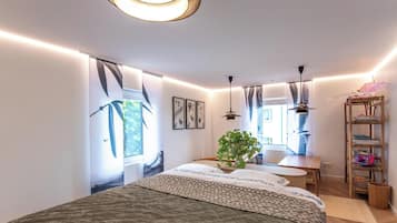 Ein modernes Schlafzimmer mit einem großen Bett, einem Holfnachtkästchen, einer hängenden Pflanze und einem Bücherregal.
