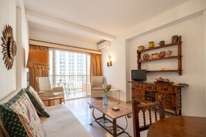 A living room with a sofa, chairs, a table, a TV, and a balcony with a view. - Perla 5 - Charming Front-Row Apartment (Fuengirola)