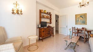 A living room with a television, wooden cabinet, wicker furniture, and a dining table with chairs. - Perla 5 - Charming Front-Row Apartment (Fuengirola)
