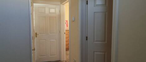 A hallway with carpeted floors and white doors.