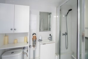 Un baño moderno con inodoro, lavamanos, espejo y ducha con mampara de vidrio.