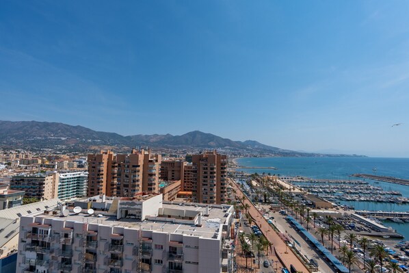 Un paisaje urbano costero con edificios altos, un puerto deportivo y un cielo azul despejado.