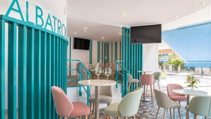 A modern interior with teal accents, a bar area, and seating arrangements. - Hotel El Puerto - Perfect Location Apartment (Fuengirola)