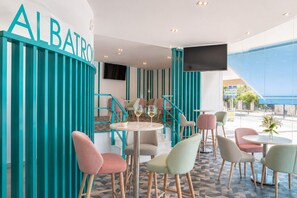 A modern interior with teal accents, a bar area, and seating arrangements. - Hotel El Puerto - Perfect Location Apartment (Fuengirola)