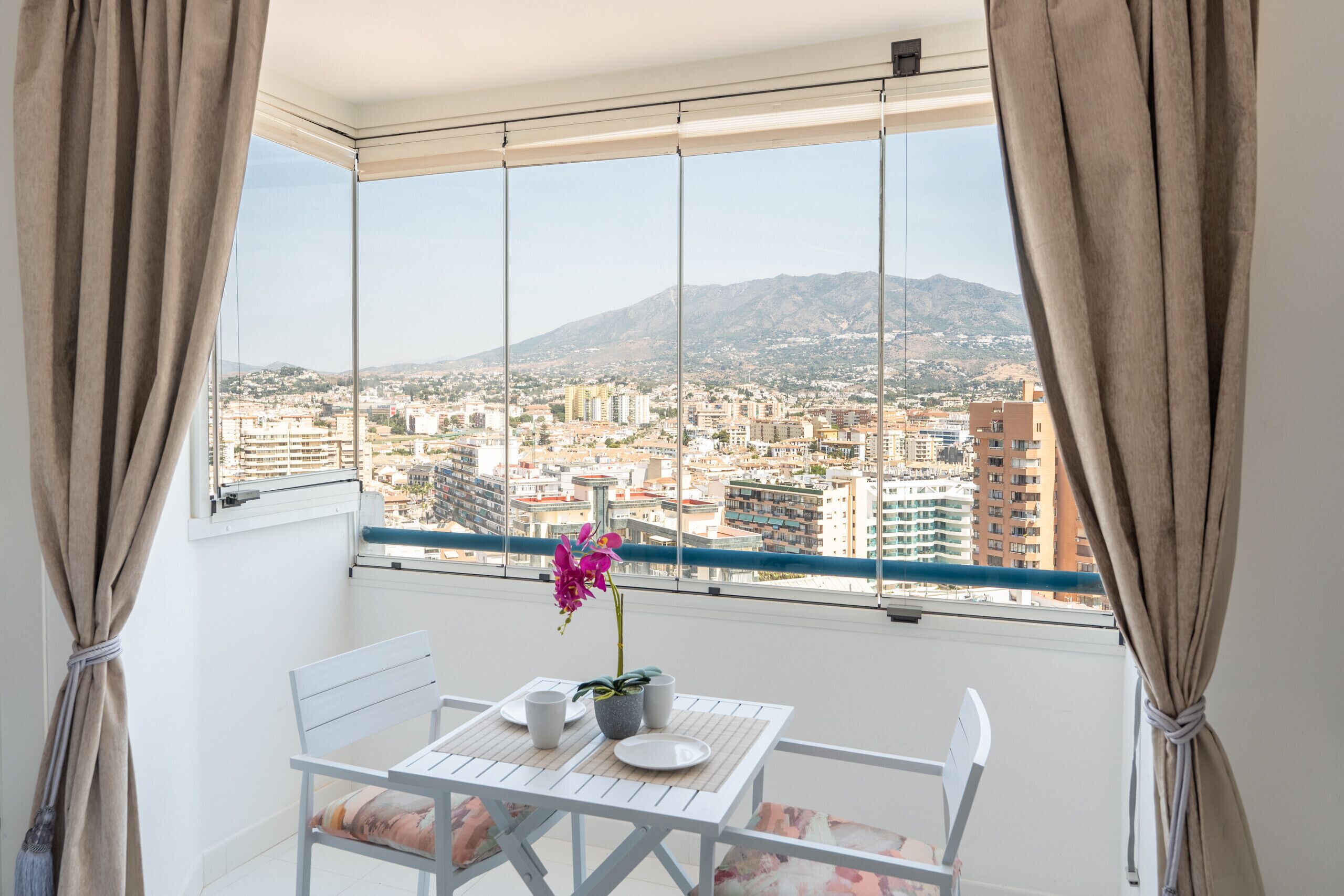 A balcony with a table, chairs, and a potted plant.