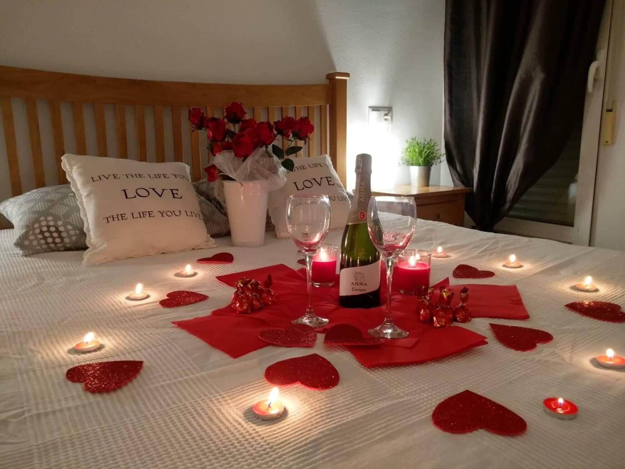 Un dormitorio con cama, velas y adornos con forma de corazón.