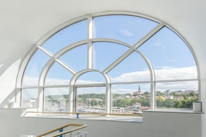 Ein Zimmer mit einem großen Bogenfenster, das Blick auf einen Hafen und Gebäude bietet.