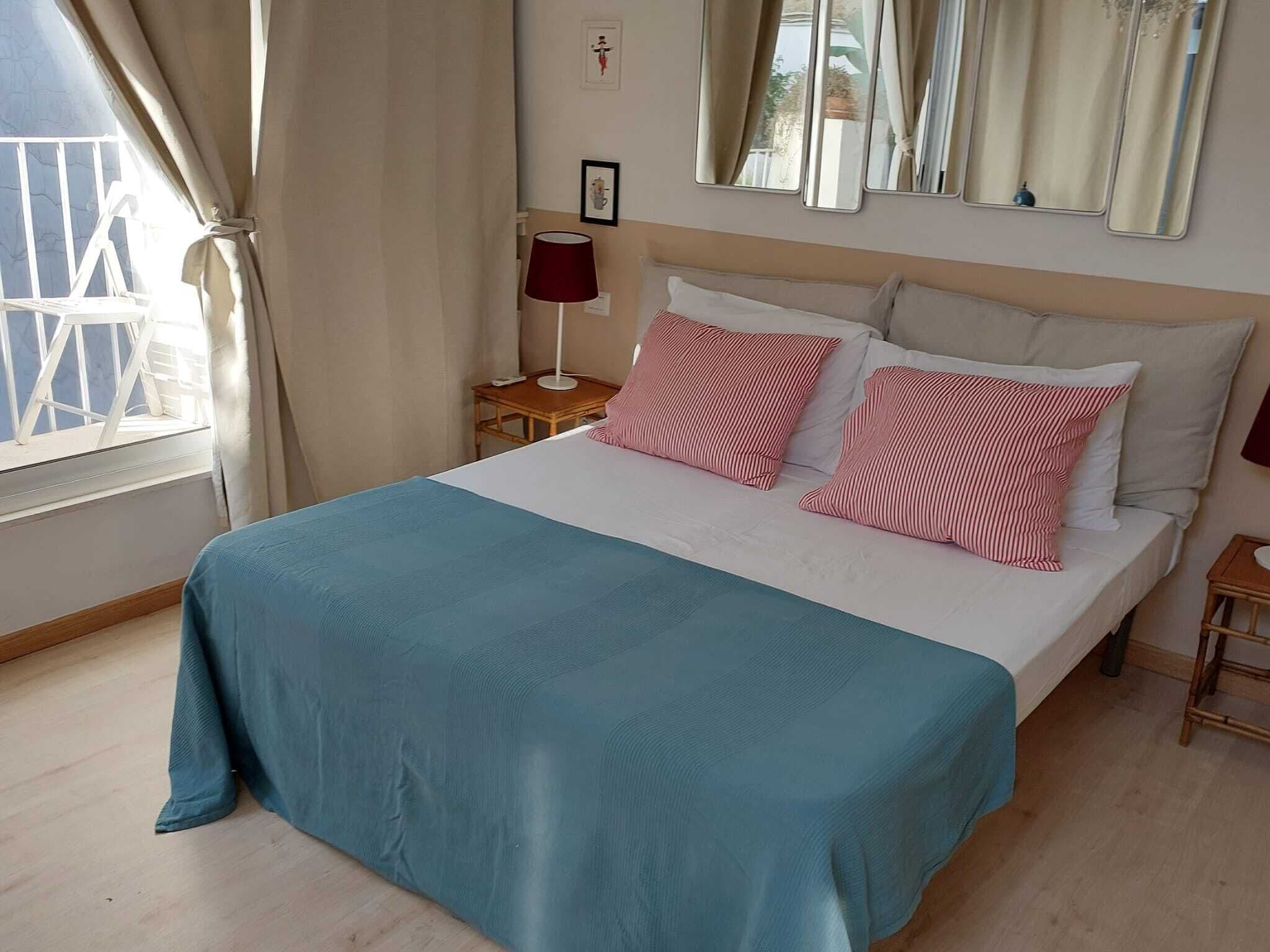 A hotel room with a bed, a nightstand, a lamp, and a window with curtains.