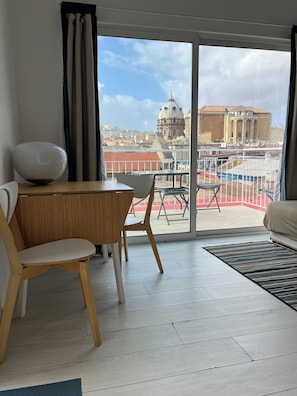 Una stanza con un tavolo da pranzo, sedie, un divano e vista su un paesaggio urbano con edifici storici.