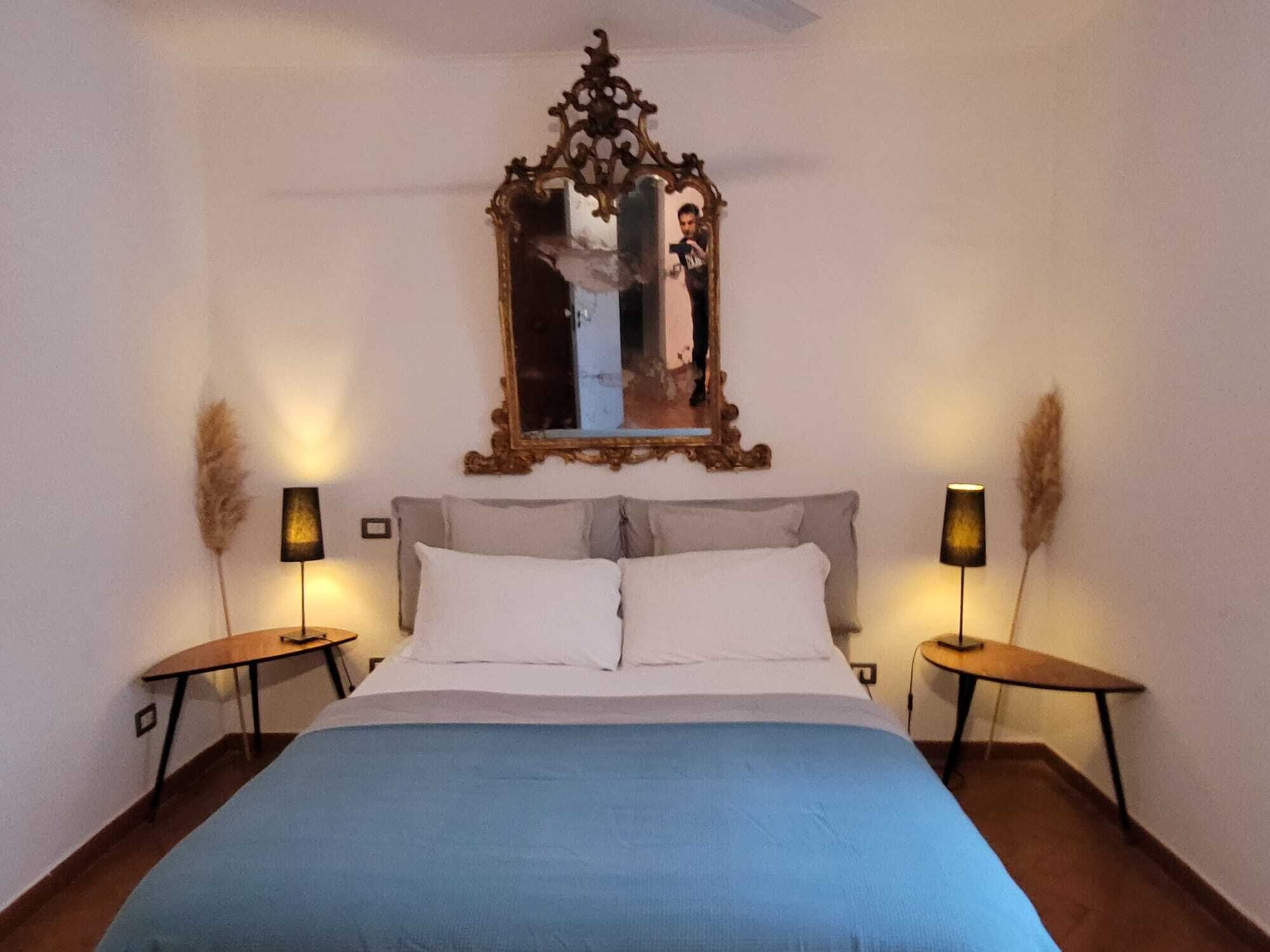 Ein Schlafzimmer mit einem großen Bett, zwei Nachttischen, einem Spiegel und zwei Lampen.
