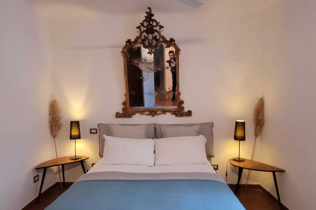 Un dormitorio con una cama grande, dos mesitas de noche, un espejo y dos lámparas.