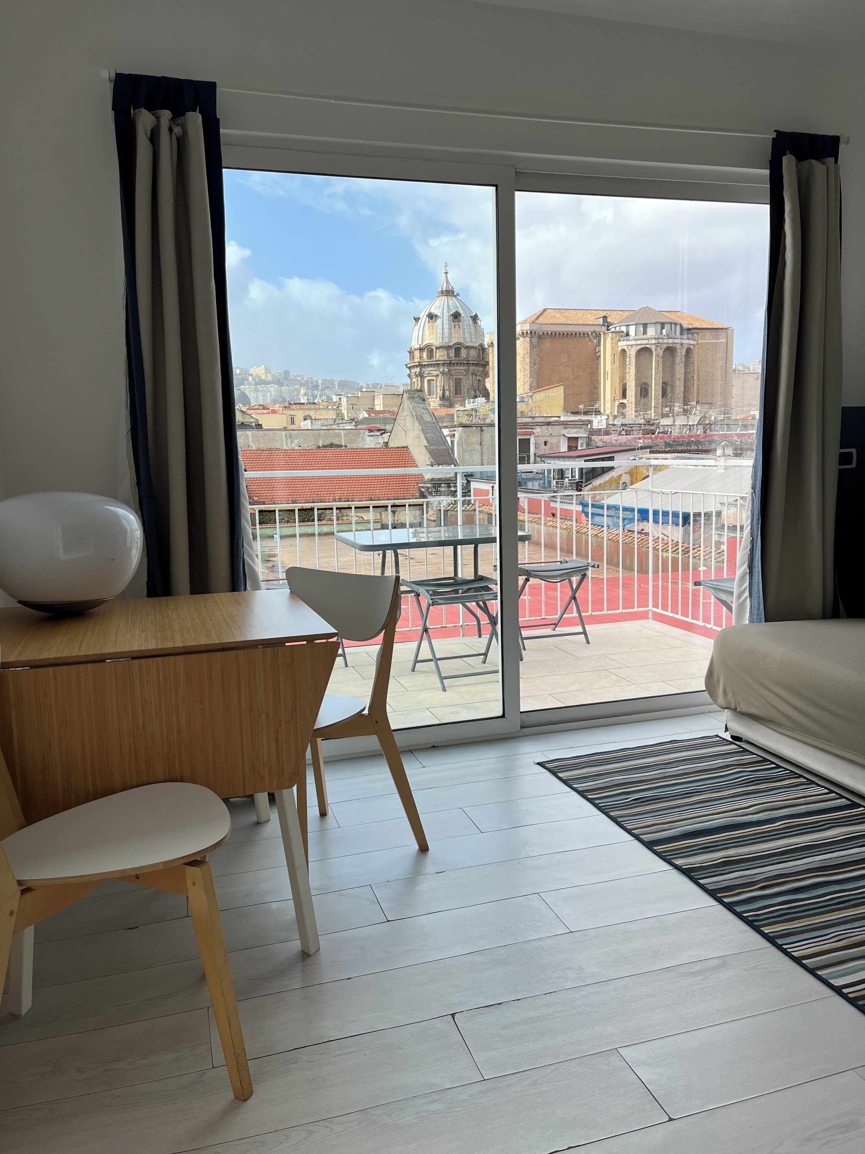 Habitación de hotel con un amplio ventanal corredero que da a una terraza al aire libre.