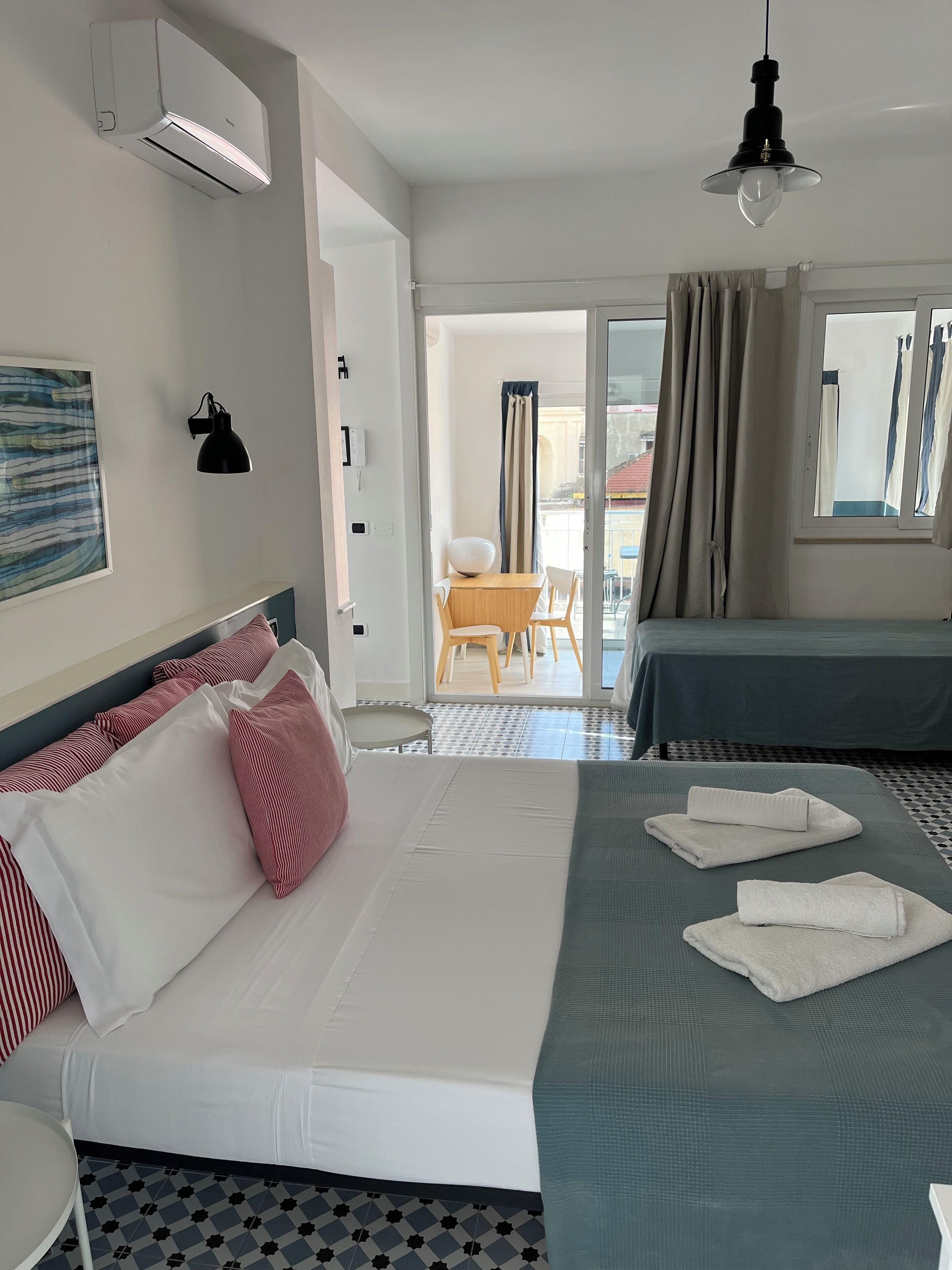 Habitación de hotel con cama, escritorio, silla, ventana con cortinas y vistas al exterior.