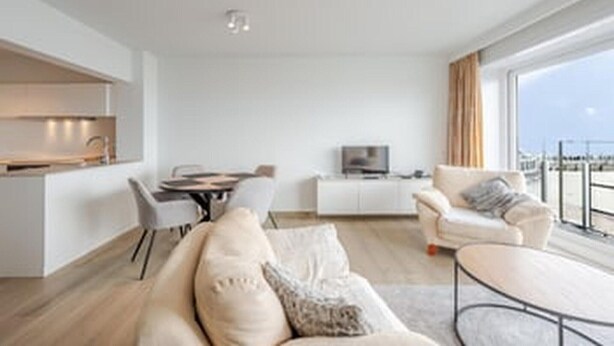 Una sala de estar moderna con sofá, mesa de centro, televisor y comedor con sillas y mesa.